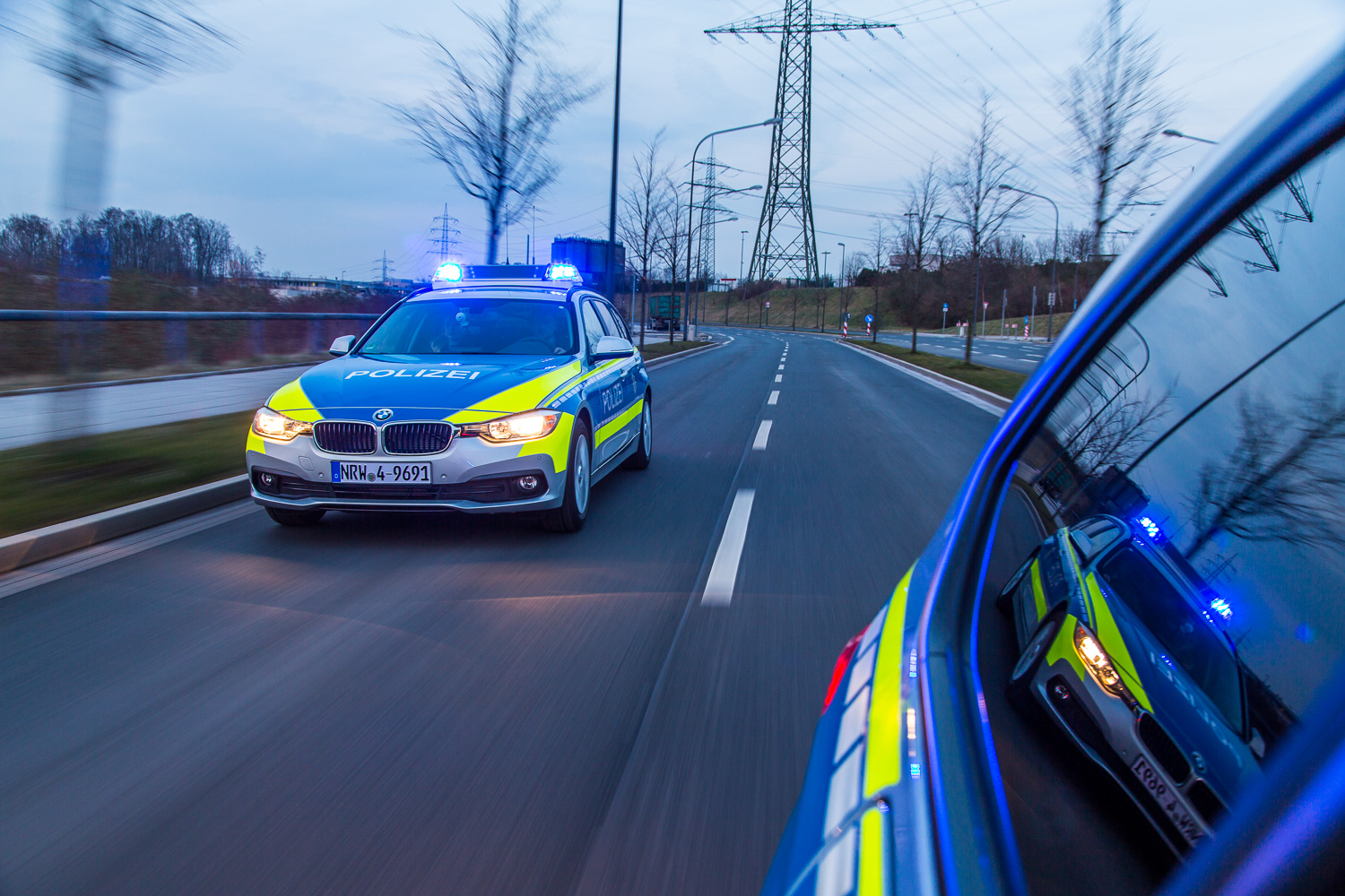 Funkstreifenwagen BMW bei Einsatzfahrt in der Dämmerung