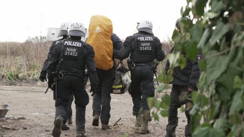 Drei Polizisten begleiten einen Aktivisten vom Lützerath Gelände.