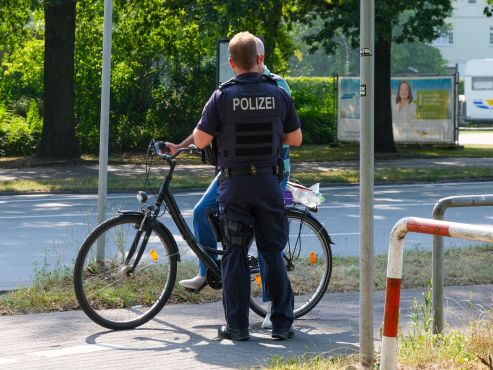 Ein Polizist spricht mit einem Fahrradfahrer. Der Herr wird von dem Polizisten verdeckt
