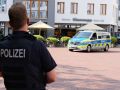 Ein Polizist von hinten, der in Richtung eines sich nahenden Streifenwagens blickt